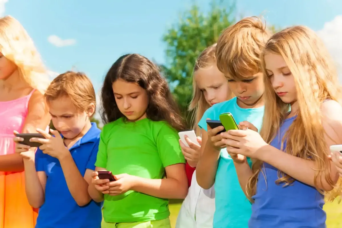 A group of kids standing together, each absorbed in their own phone